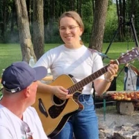 Ewa Banachiewicz gra na gitarze podczas imprezy plenerowej z ogniskiem